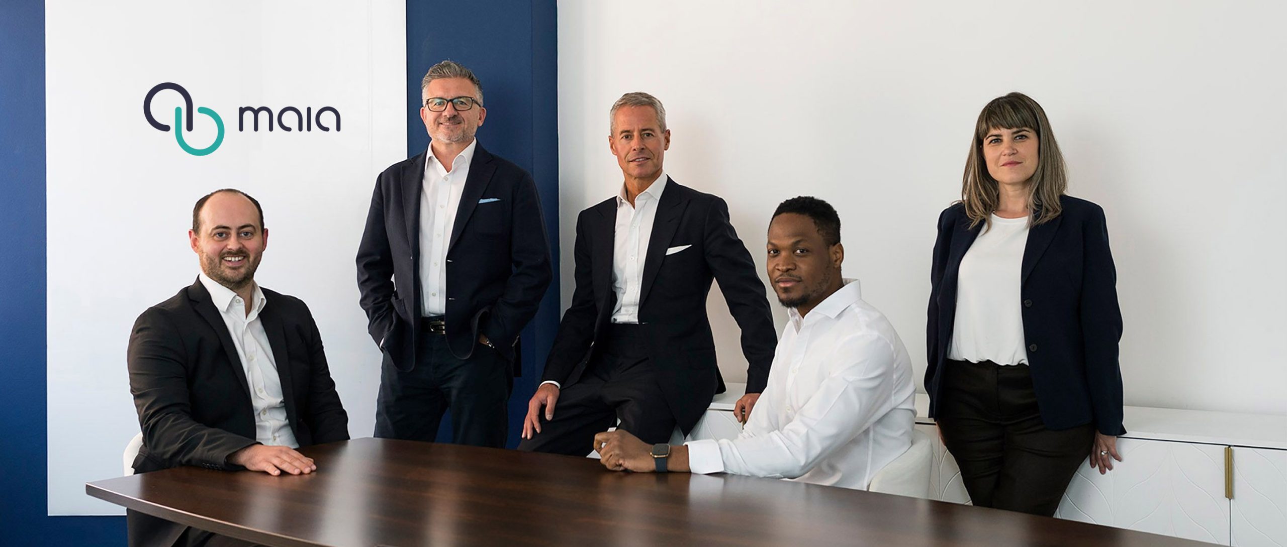 MAIA team members in the company office beside the MAIA logo